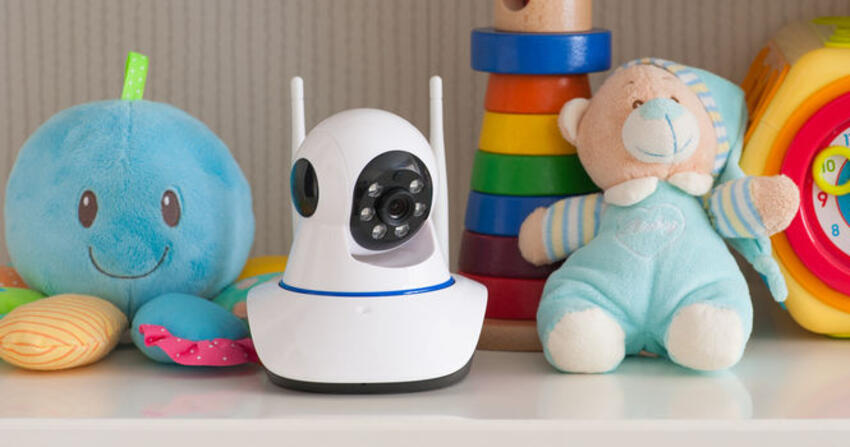 Small white indoor Wi-Fi camera on a shelf next to stuffed toys